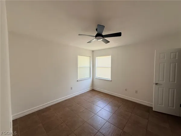an empty room with a ceiling fan and window