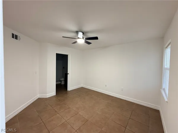 an empty room with a ceiling fan and a window