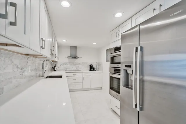 a kitchen with white cabinets and stainless steel appliances