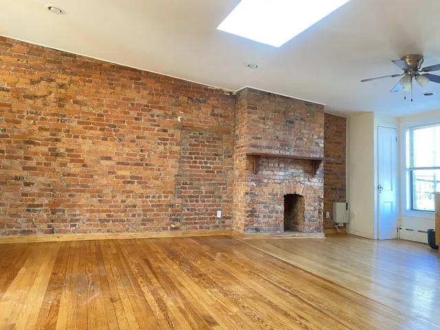 a view of empty room with wooden floor and fireplace
