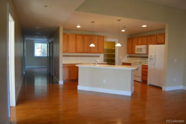a view of a kitchen with kitchen island a sink wooden floor and a refrigerator