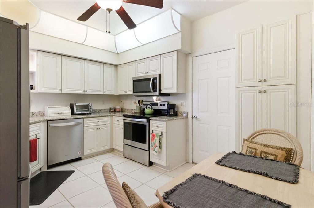6640 Pineview Terrace, Unit 6640 Bradenton, FL 34203 - Photo 17 of 80 a kitchen with stainless steel appliances granite countertop a stove a sink dishwasher a refrigerator and white cabinets with wooden floor
