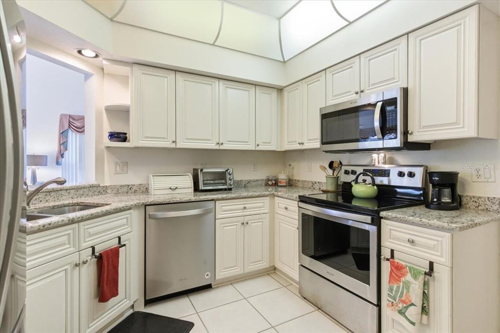 6640 Pineview Terrace, Unit 6640 Bradenton, FL 34203 - Photo 19 of 80 a kitchen with stainless steel appliances granite countertop a stove a sink and a microwave