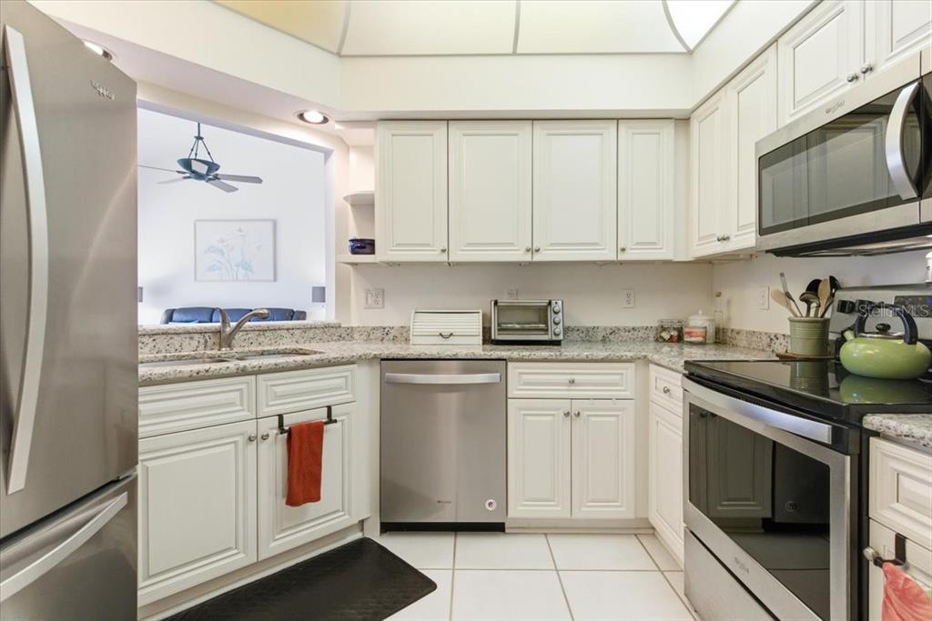 6640 Pineview Terrace, Unit 6640 Bradenton, FL 34203 - Photo 21 of 80 a kitchen with granite countertop white cabinets white stainless steel appliances with a sink and dishwasher