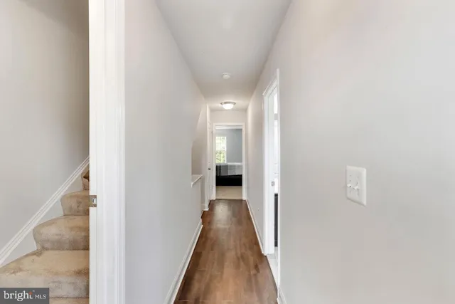 a view of a hallway with wooden floor and a bathroom