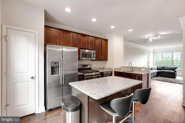 a kitchen with stainless steel appliances granite countertop a table chairs stove and refrigerator