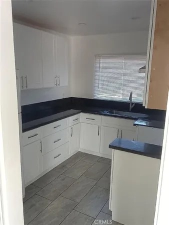 a kitchen with granite countertop white cabinets and sink