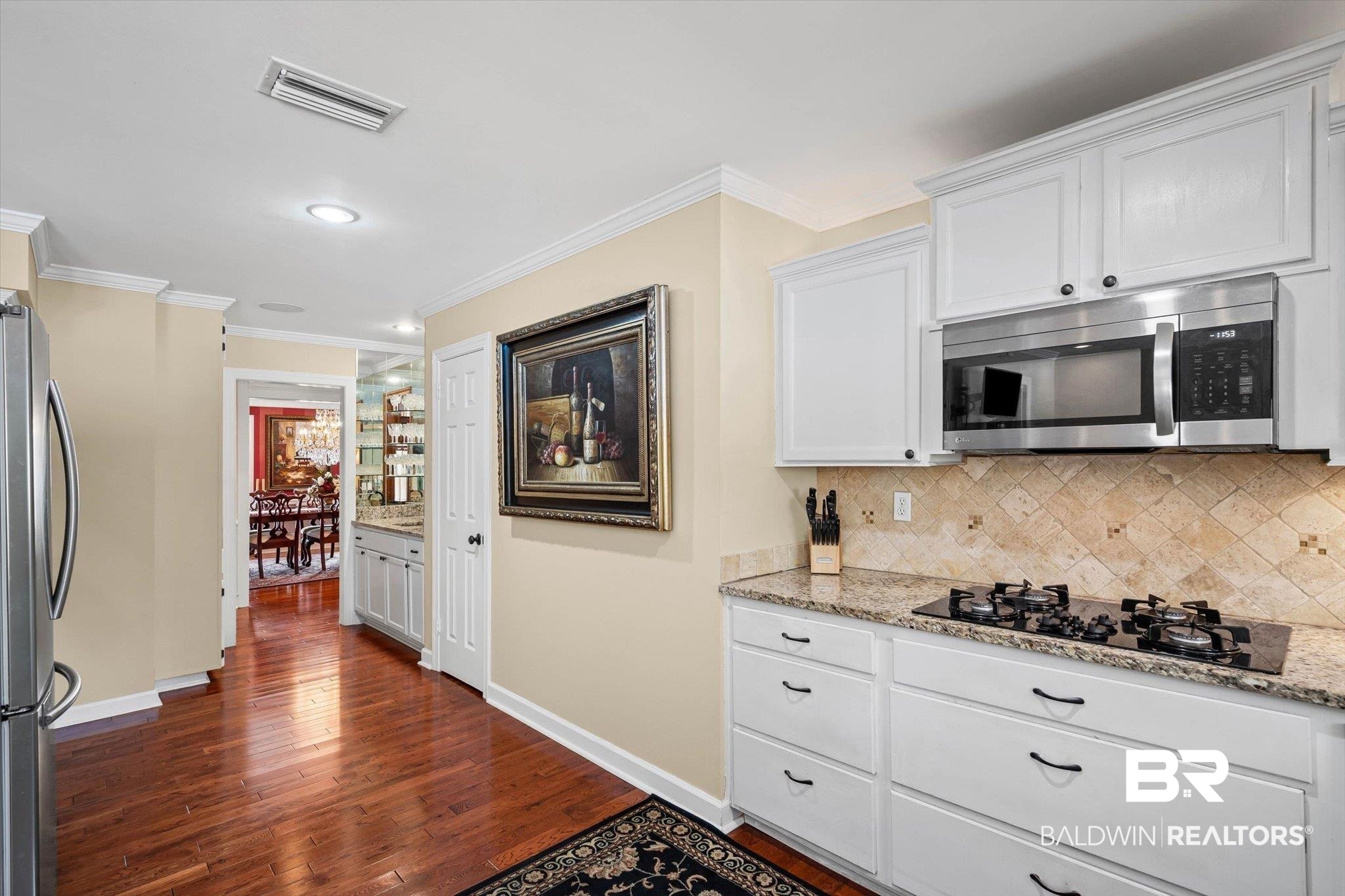 1517 Ridgeland Road East Mobile, AL 36695 - Photo 11 of 39 Kitchen featuring light stone counters, tasteful backsplash, stainless steel appliances, ornamental molding, and white cabinetry