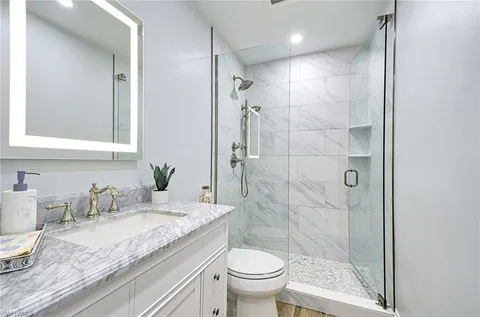 a bathroom with a granite countertop sink a toilet and shower