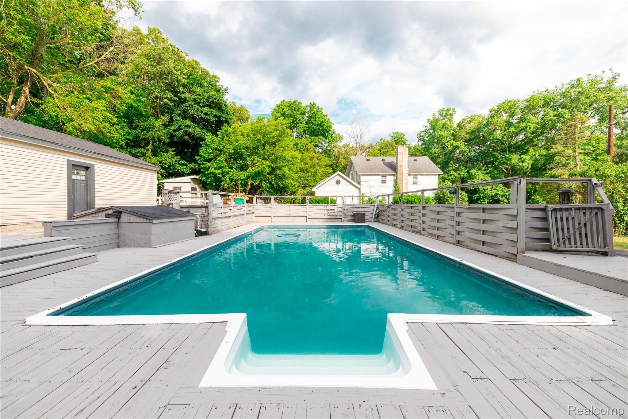 4860 Blue Bush Road Monroe, MI 48162 - Photo 41 of 59 In-ground swimming pool with integrated steps, surrounded by a gray wood-finish deck