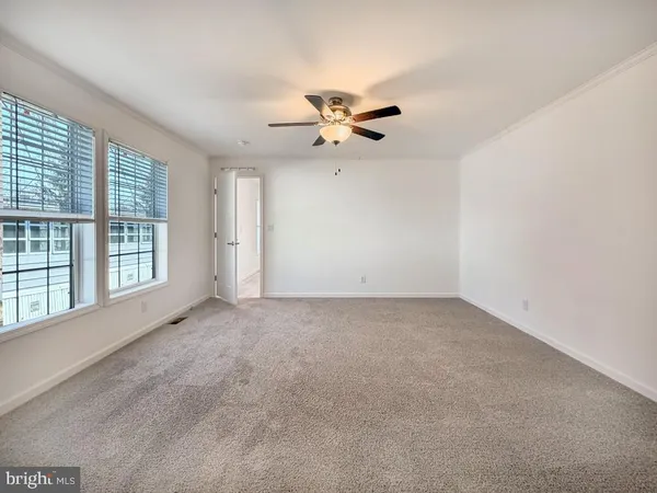 an empty room with chandelier fan and windows