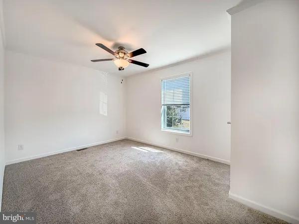 an empty room with windows and chandelier fan