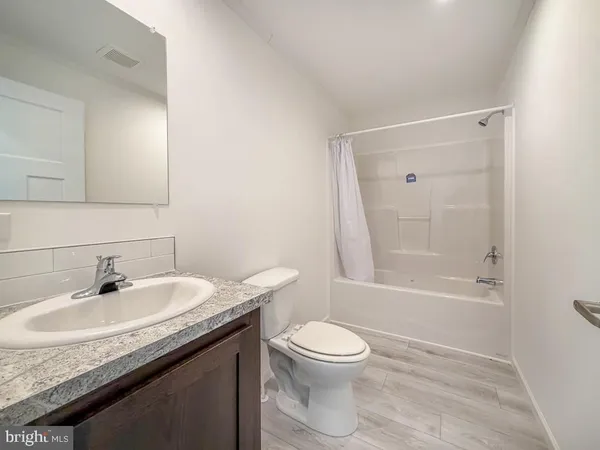 a bathroom with a granite countertop sink a toilet and shower
