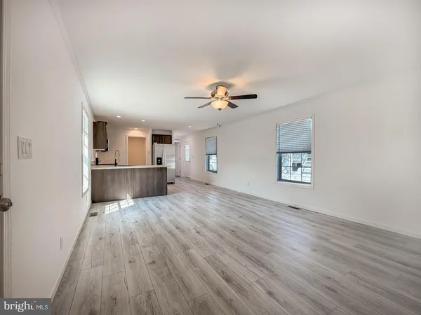 a view of a kitchen and an empty room with wooden floor