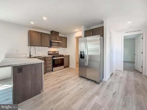a kitchen with stainless steel appliances granite countertop a refrigerator a sink a stove and oven