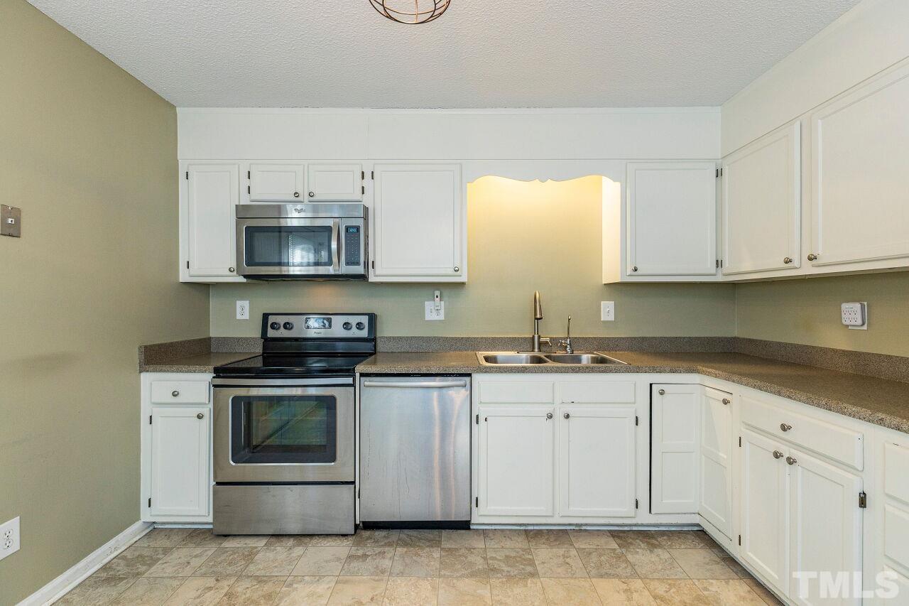 7902 Yester Court Raleigh, NC 27615 - Photo 14 of 30 a kitchen with granite countertop white cabinets and stainless steel appliances