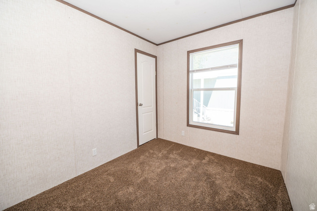 2491 Highway 89, Unit 403 Pleasant View, UT 84404 - Photo 23 of 32 Neutral-toned walls featuring a textured finish, brown trim, and plush brown carpeting