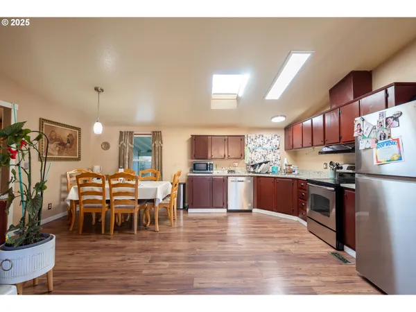 a kitchen with stainless steel appliances kitchen island granite countertop a table chairs and a refrigerator