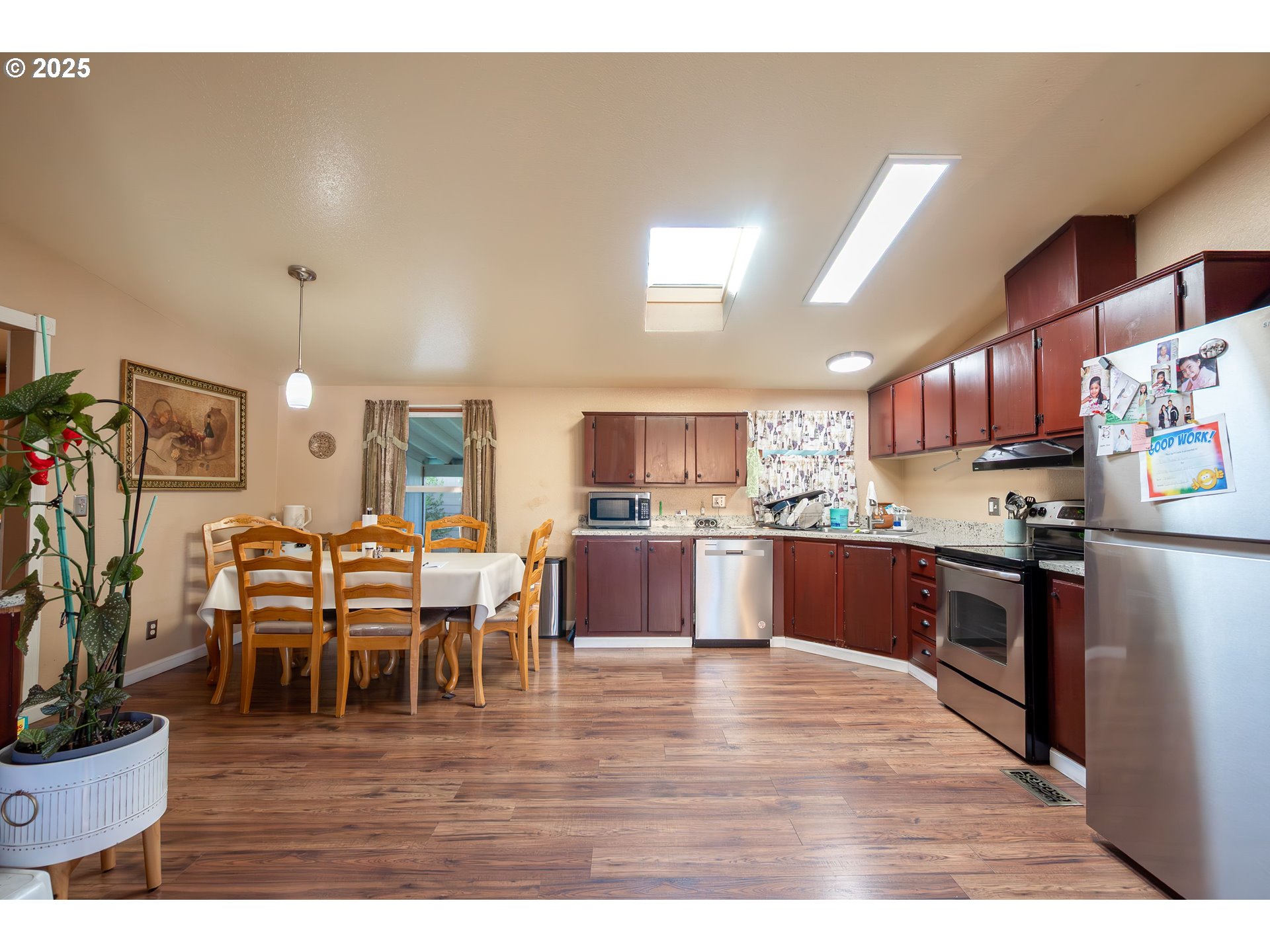 11105 Main Street Northeast, Unit 6 Donald, OR 97020 - Photo 8 of 23 a kitchen with stainless steel appliances kitchen island granite countertop a table chairs and a refrigerator