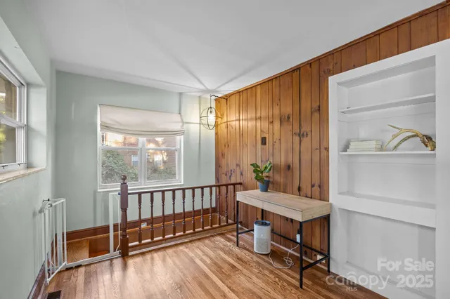 a view of a hallway with wooden floor and furniture