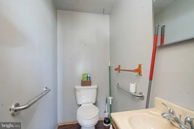a white toilet sitting next to a bathroom sink and a wooden floor