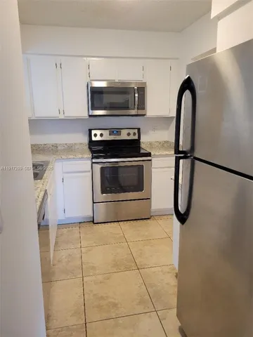 a kitchen with granite countertop a stove a microwave and a refrigerator