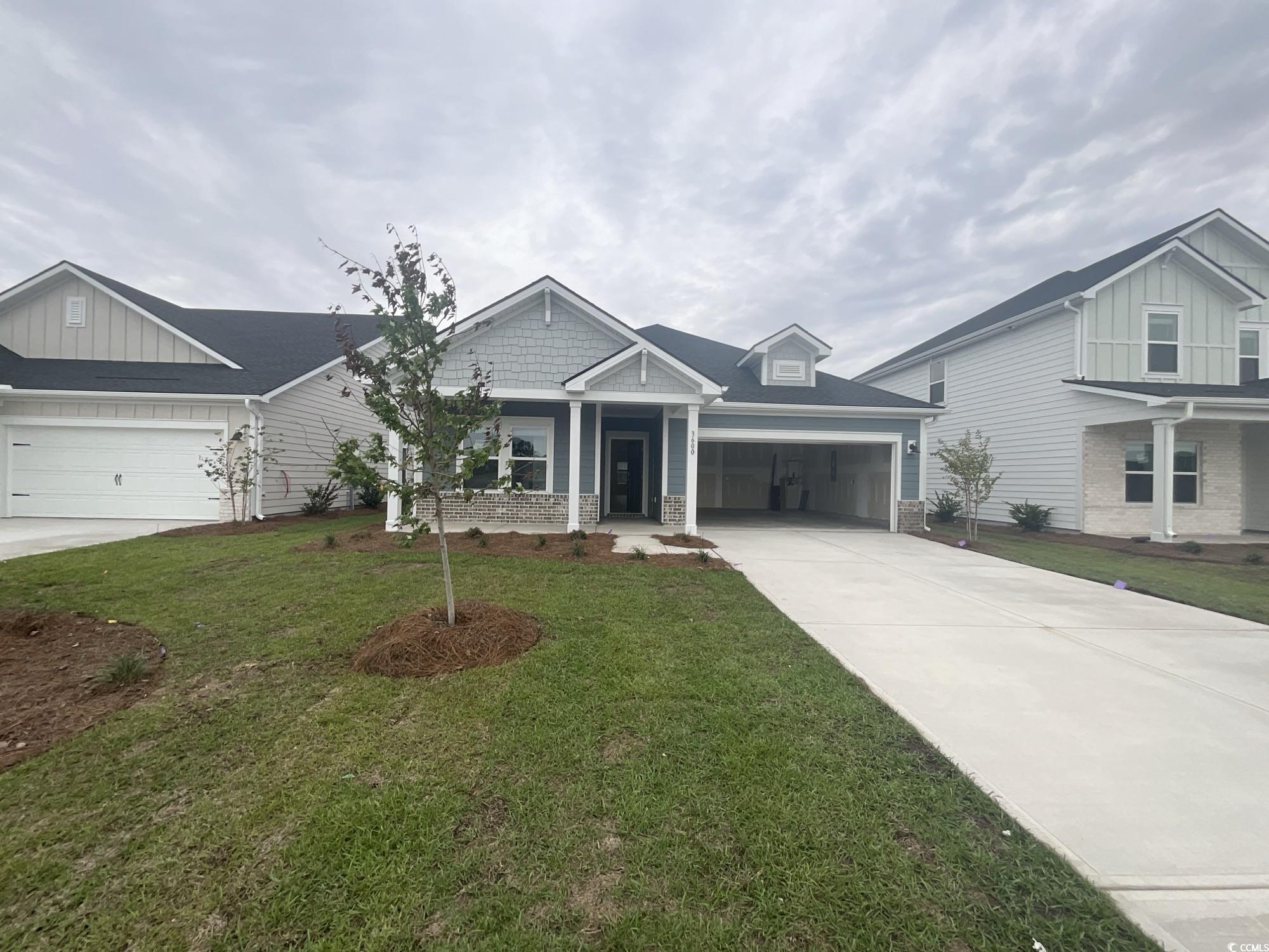 Craftsman-style house with concrete driveway, stone siding, a porch, a front lawn, and a garage
