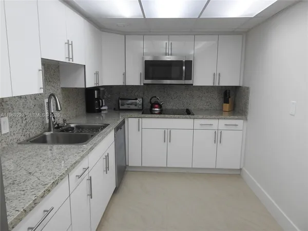a kitchen with white cabinets a sink and dishwasher