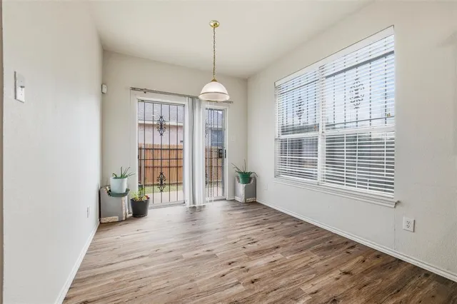a view of an empty room with a window and wooden floor