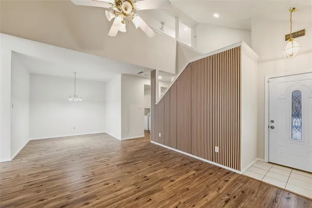 a view of an empty room with wooden floor and a ceiling fan