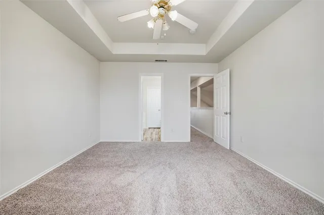 an empty room with chandelier fan and windows