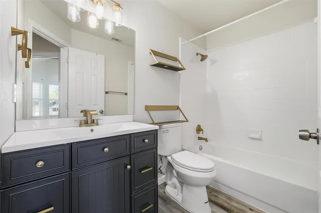 a bathroom with a toilet a sink a mirror a bathtub and vanity