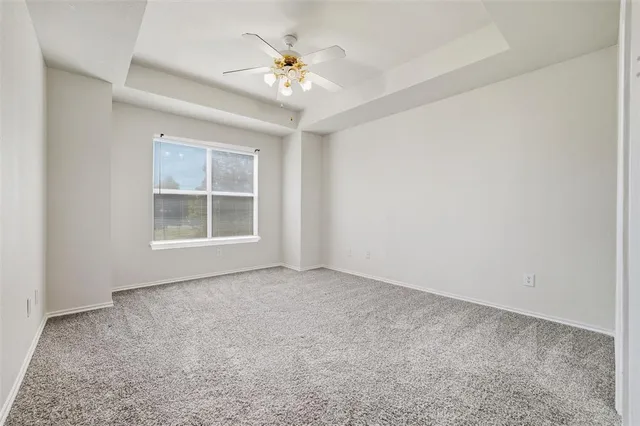 an empty room with windows and chandelier fan