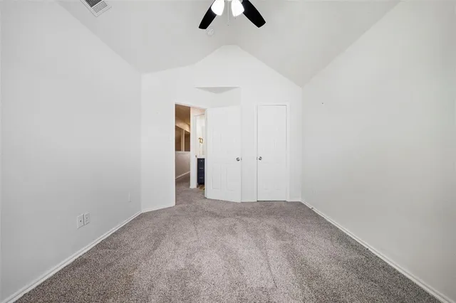 an empty room with a ceiling fan and carpet