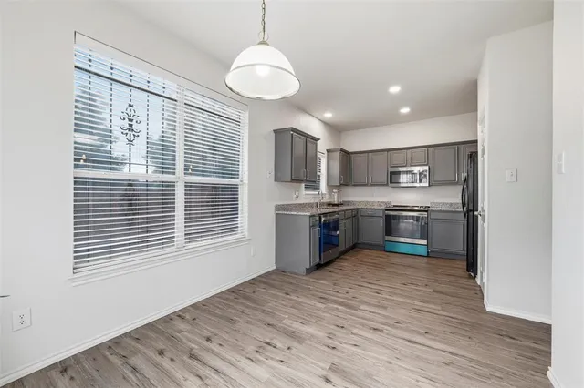 a kitchen with stainless steel appliances granite countertop a sink cabinets and wooden floor