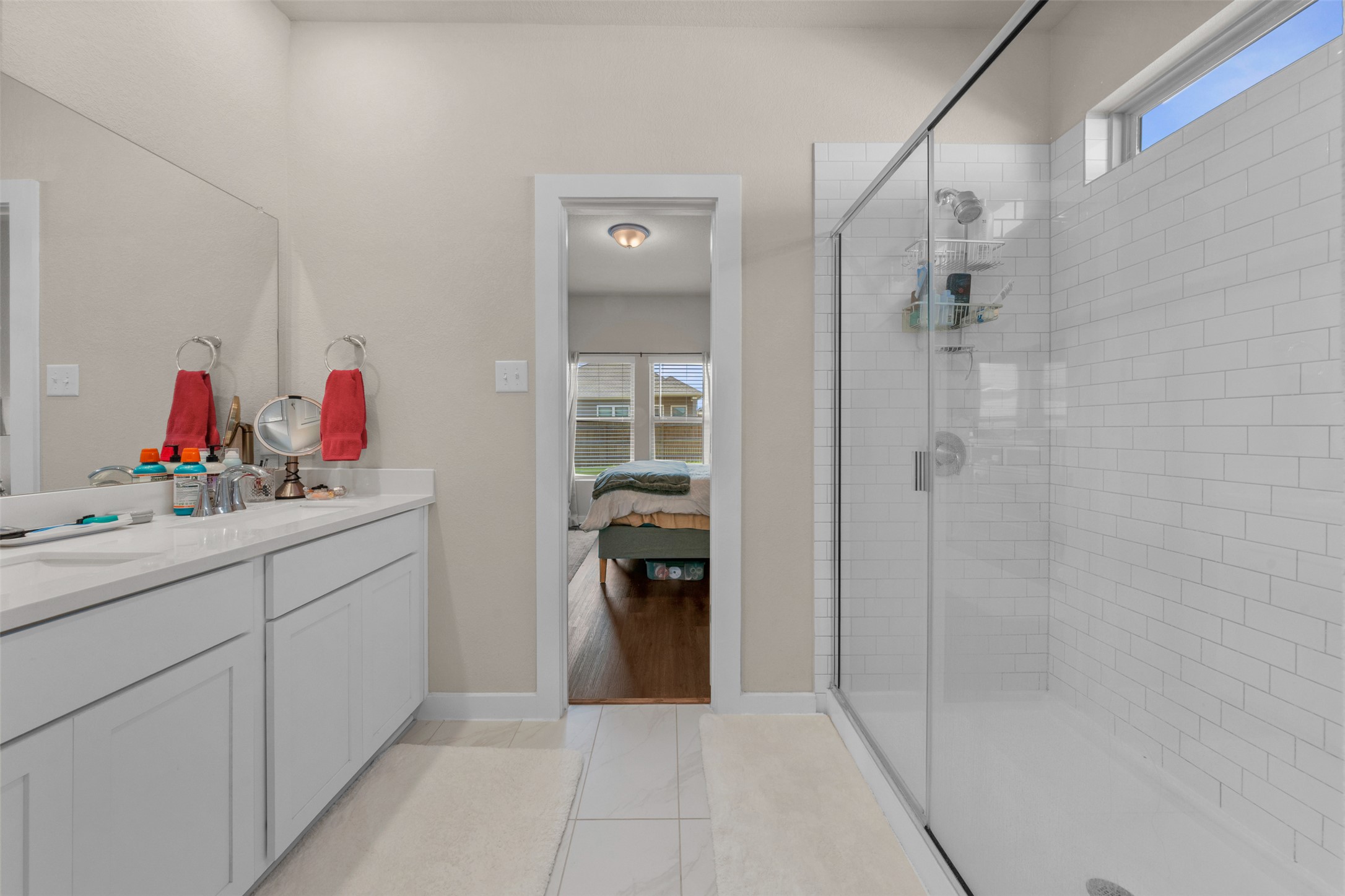 236 Lazy Lizzy Road Jarrell, TX 76537 - Photo 15 of 27 A well-appointed bathroom offers a dual vanity, a spacious glass-enclosed shower, and convenient access to the primary bedroom.