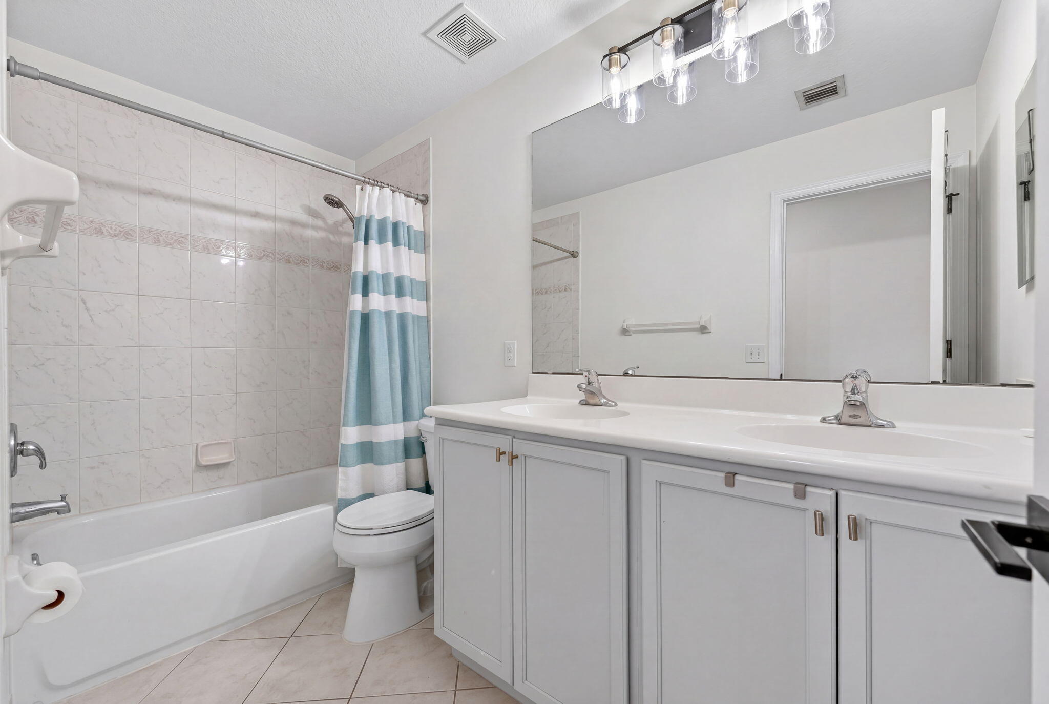 5951 Manchester Way Tamarac, FL 33321 - Photo 5 of 41 a bathroom with a sink a toilet a mirror a bathtub and shower