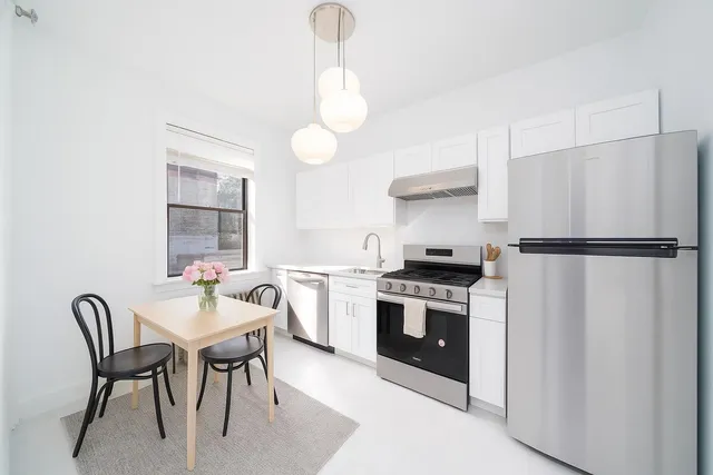 a kitchen with a table chairs a stove and a window
