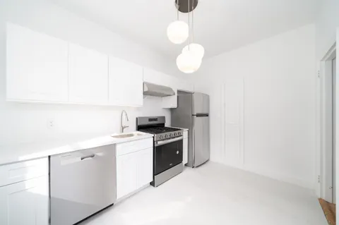 a kitchen with a stove cabinets and wooden floor