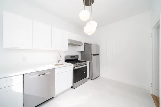 a kitchen with a stove cabinets and wooden floor
