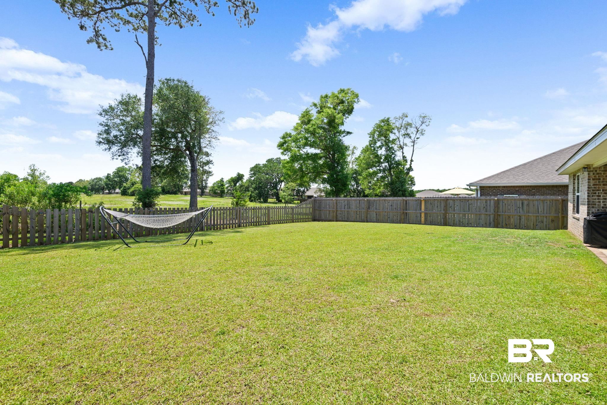 8021 Valor Rdg Way North Mobile, AL 36619 - Photo 9 of 34 Expansive green lawn enclosed by a wooden privacy fence and a picket fence