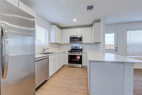 a kitchen with kitchen island a sink stainless steel appliances and cabinets