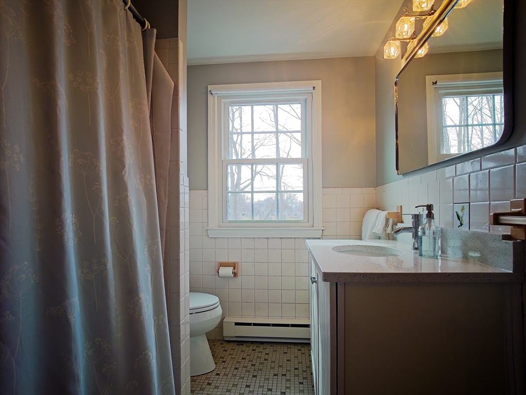57 Sylvan Street, Unit 5D Danvers, MA 01923 - Photo 12 of 15 a bathroom with a granite countertop sink toilet and mirror