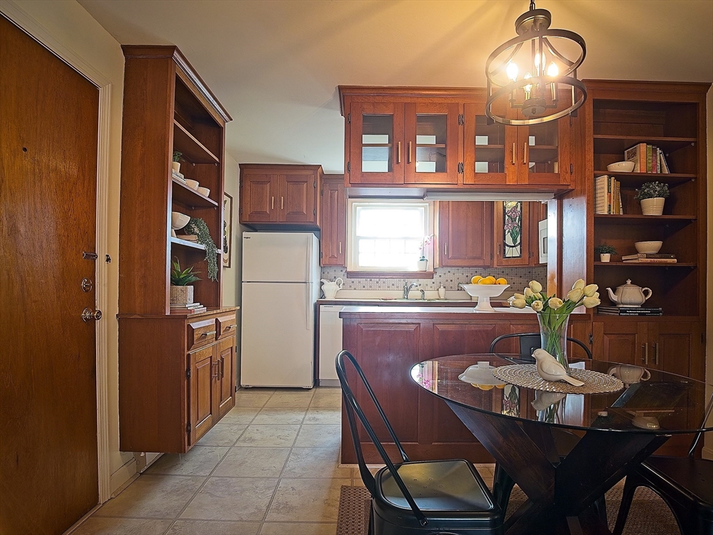 57 Sylvan Street, Unit 5D Danvers, MA 01923 - Photo 6 of 15 a dining room with furniture a chandelier and kitchen view