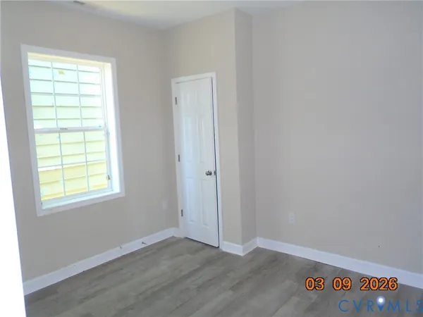 an empty room with wooden floor and windows