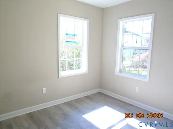 an empty room with wooden floor and windows