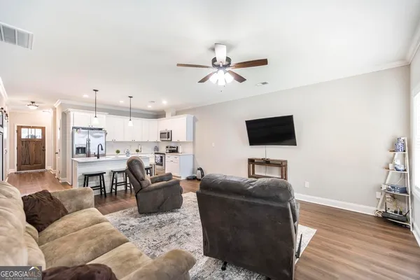 a living room with furniture a flat screen tv and kitchen view