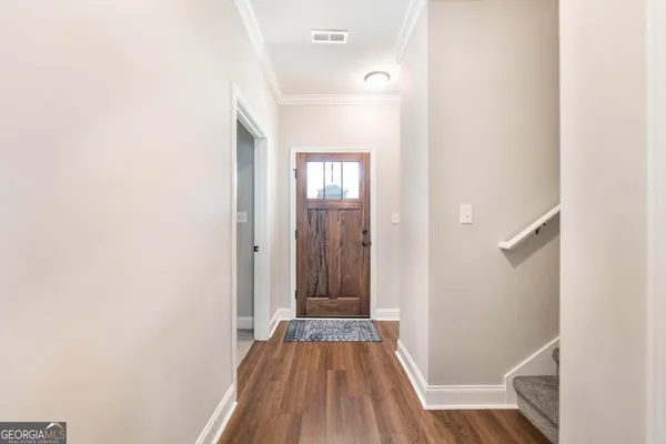 a view of a hallway with wooden floor and a bathroom