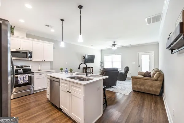 a kitchen with a sink stove cabinets and wooden floor
