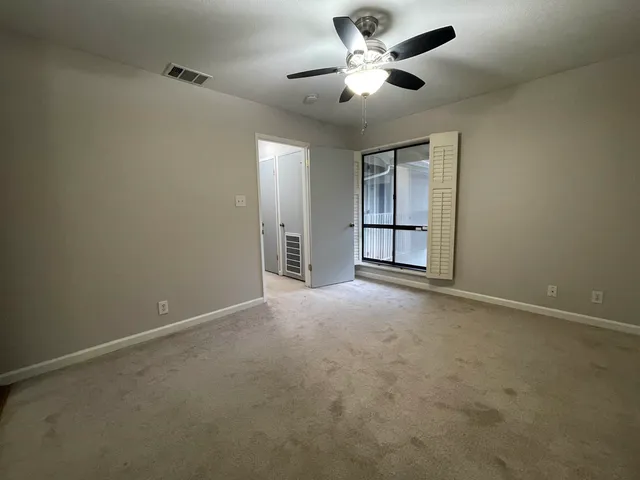 an empty room with a ceiling fan and windows
